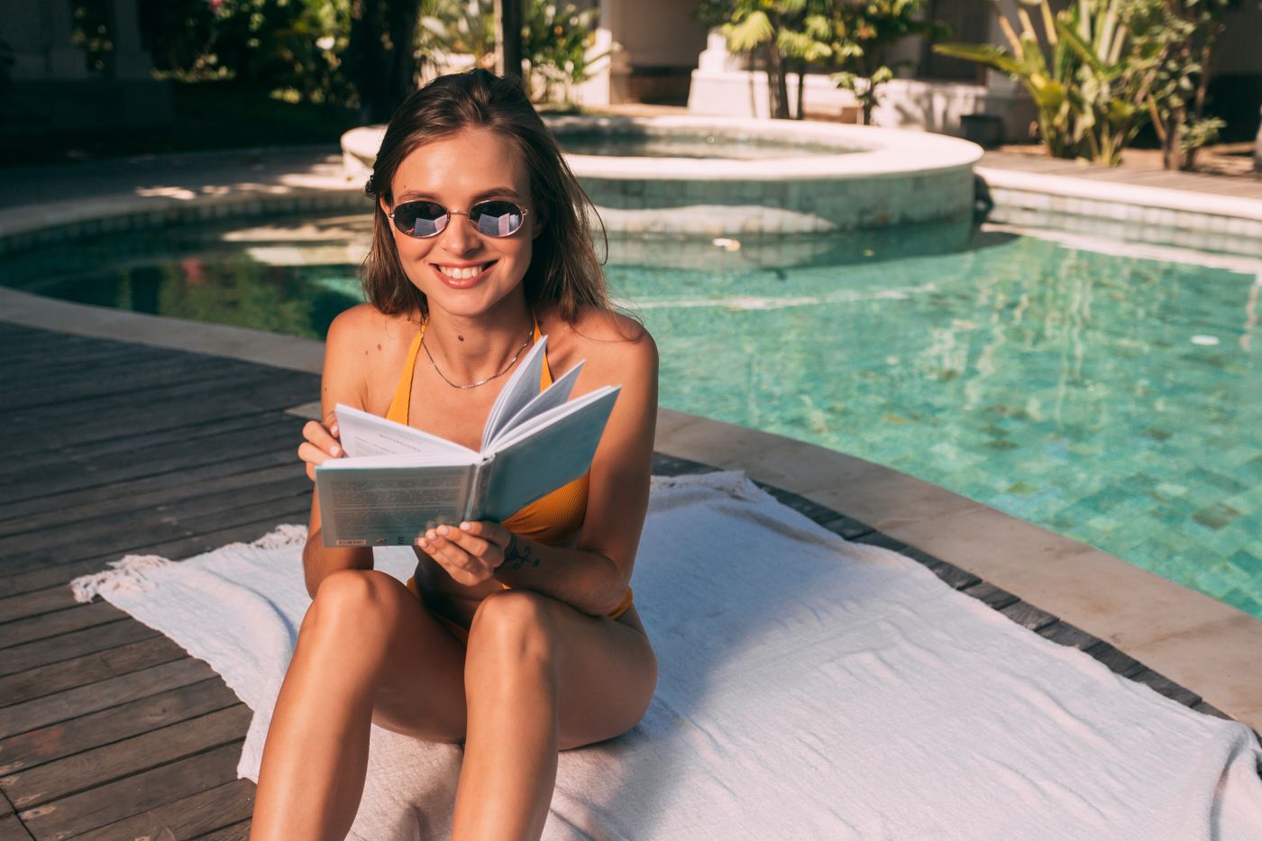 A woman enjoying a book beside a swimming pool
