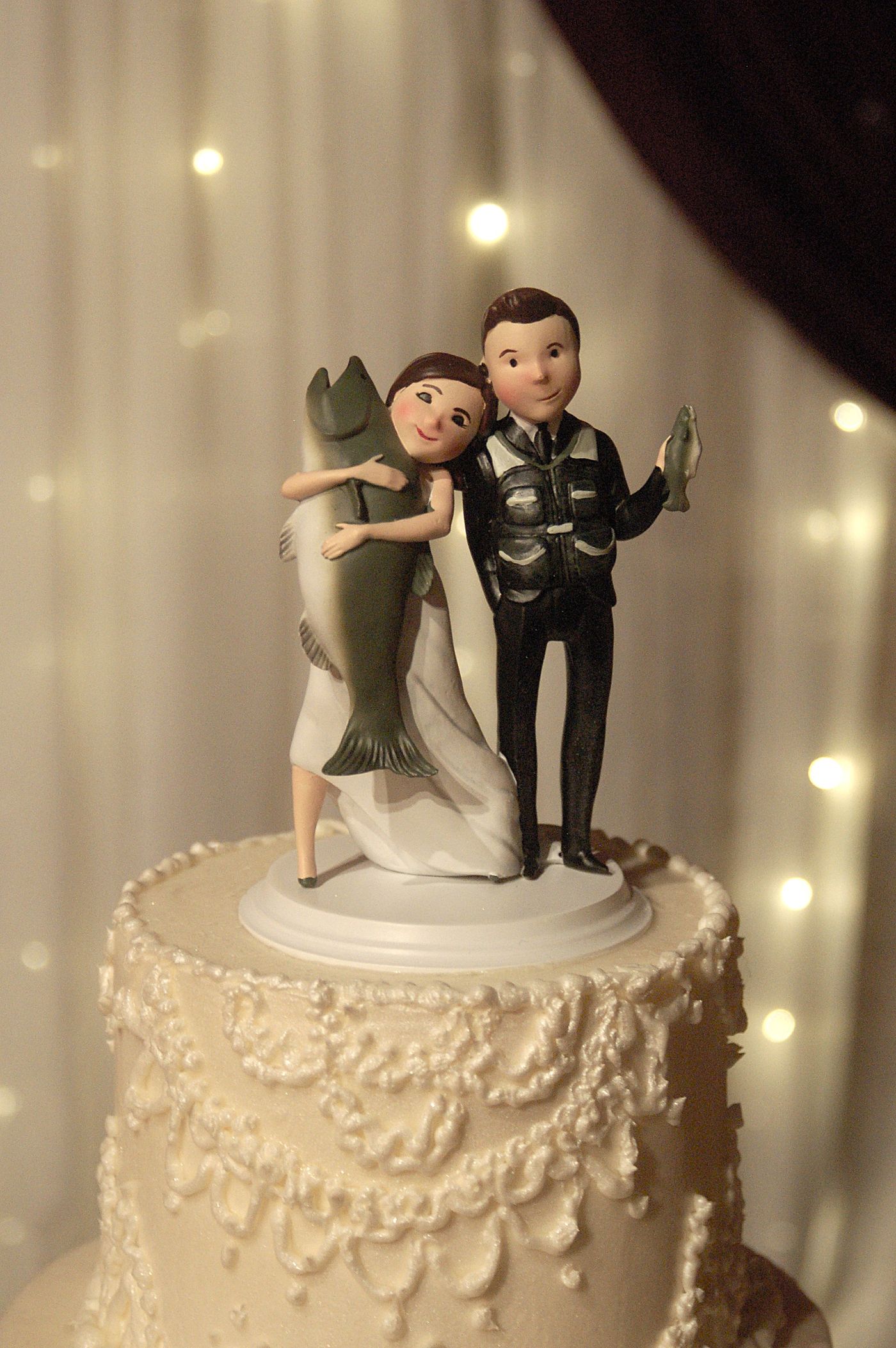 A playful fishing-themed bride and groom cake topper
