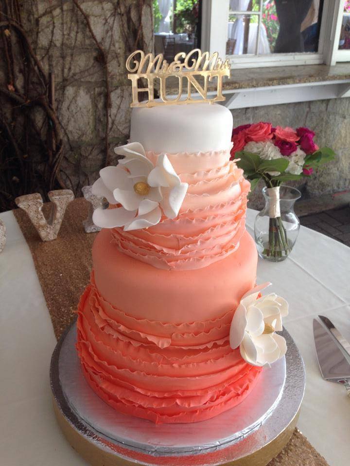 A pink tiered wedding cake decorated with white flowers