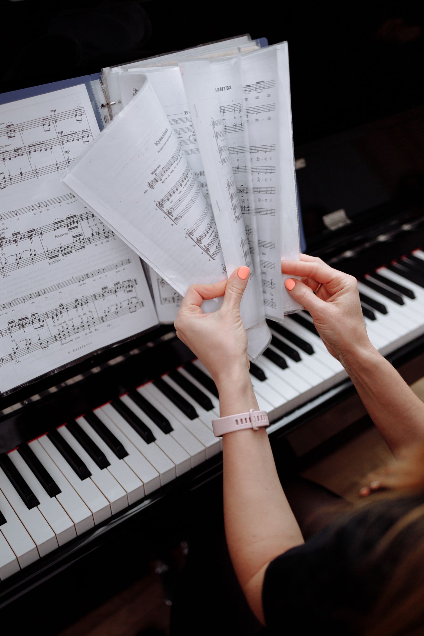 Hands turning the pages of sheet music at a piano