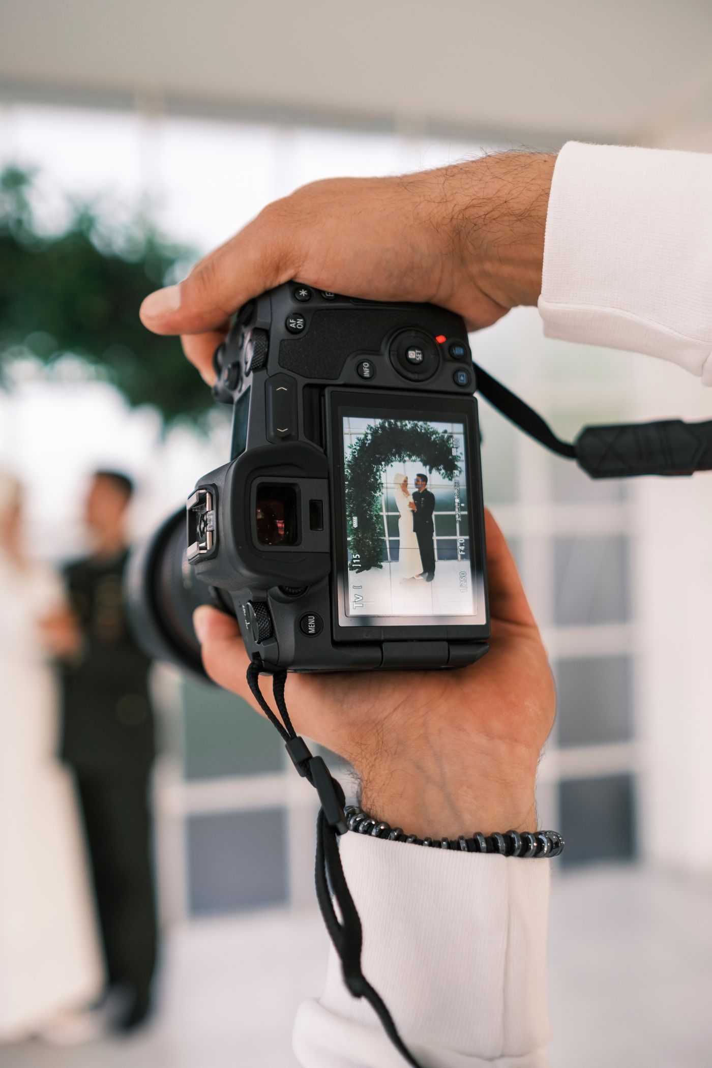 A wedding photographer framing a couple through a camera display