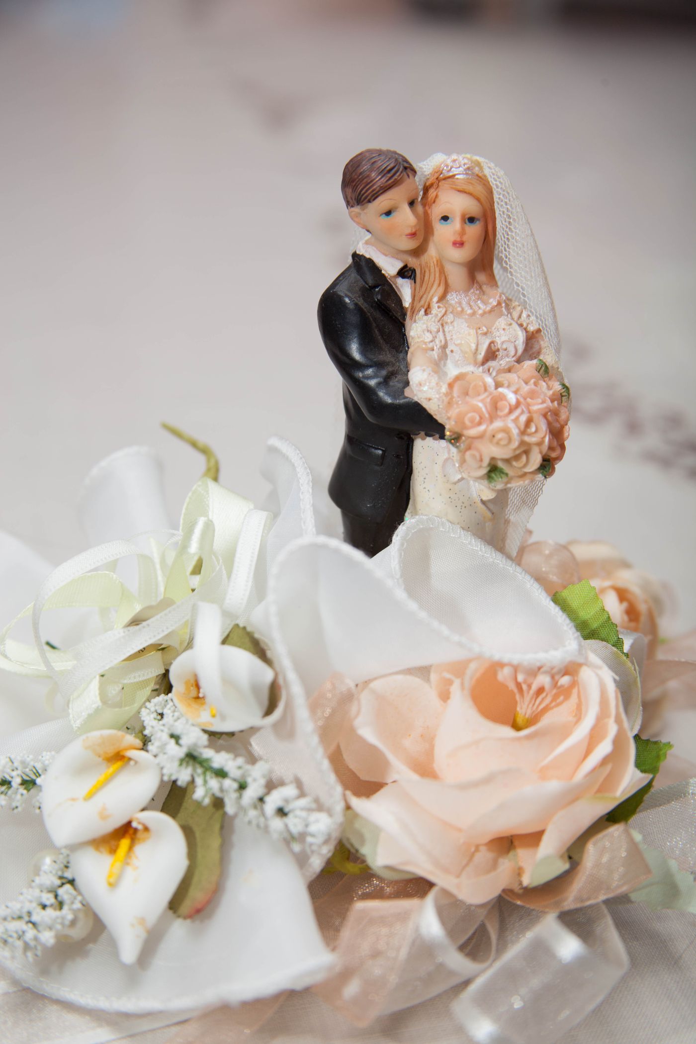A wedding cake topper framed by roses and calla lilies