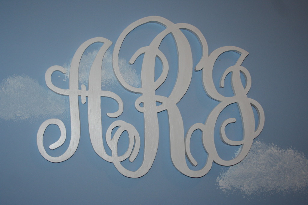 A decorative white monogram against a pale blue background