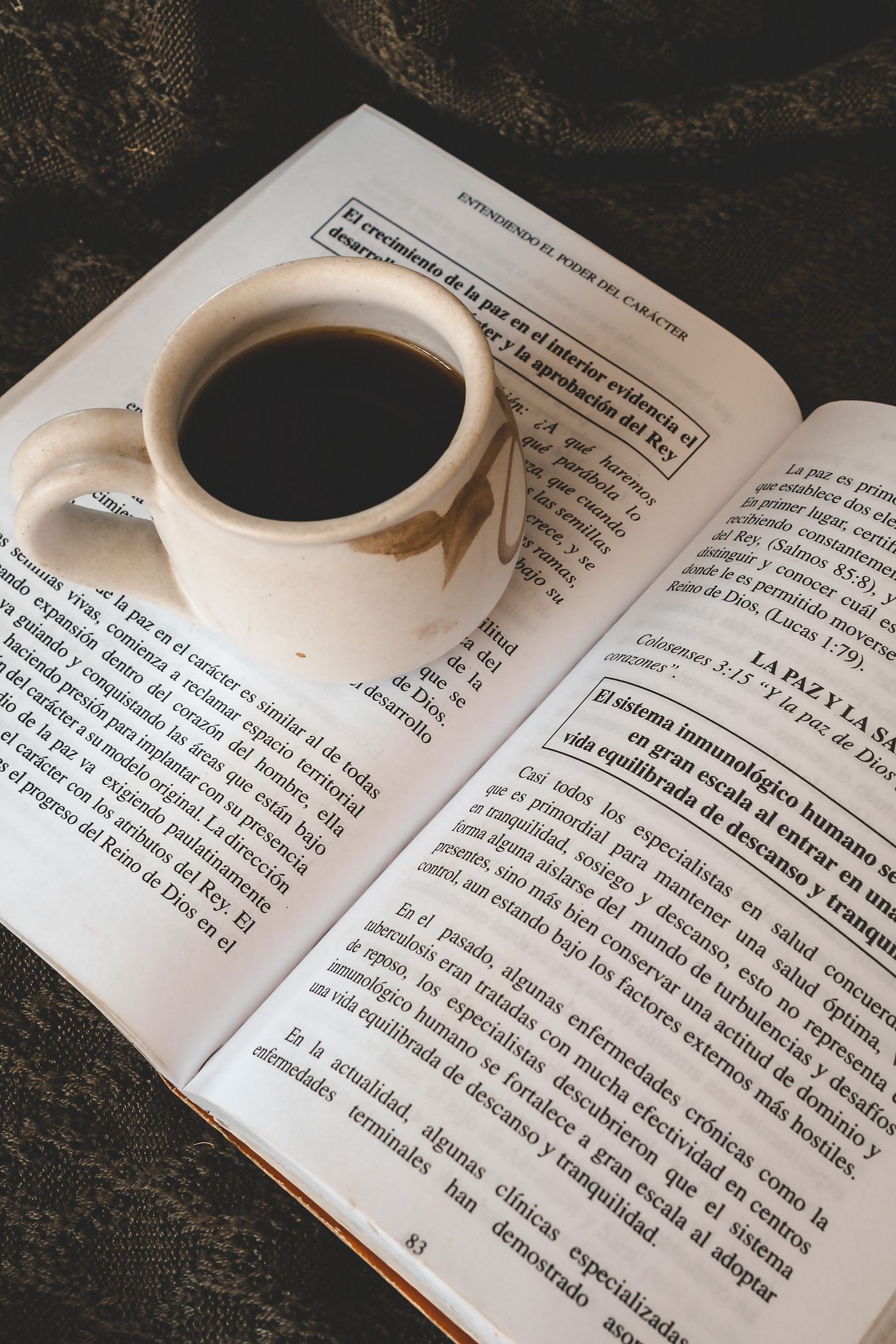 A cup of coffee resting beside an open book