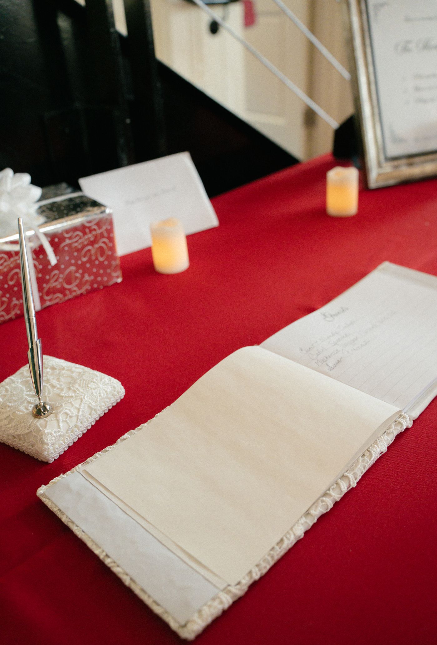 A white wedding guest book and pen on a red tablecloth