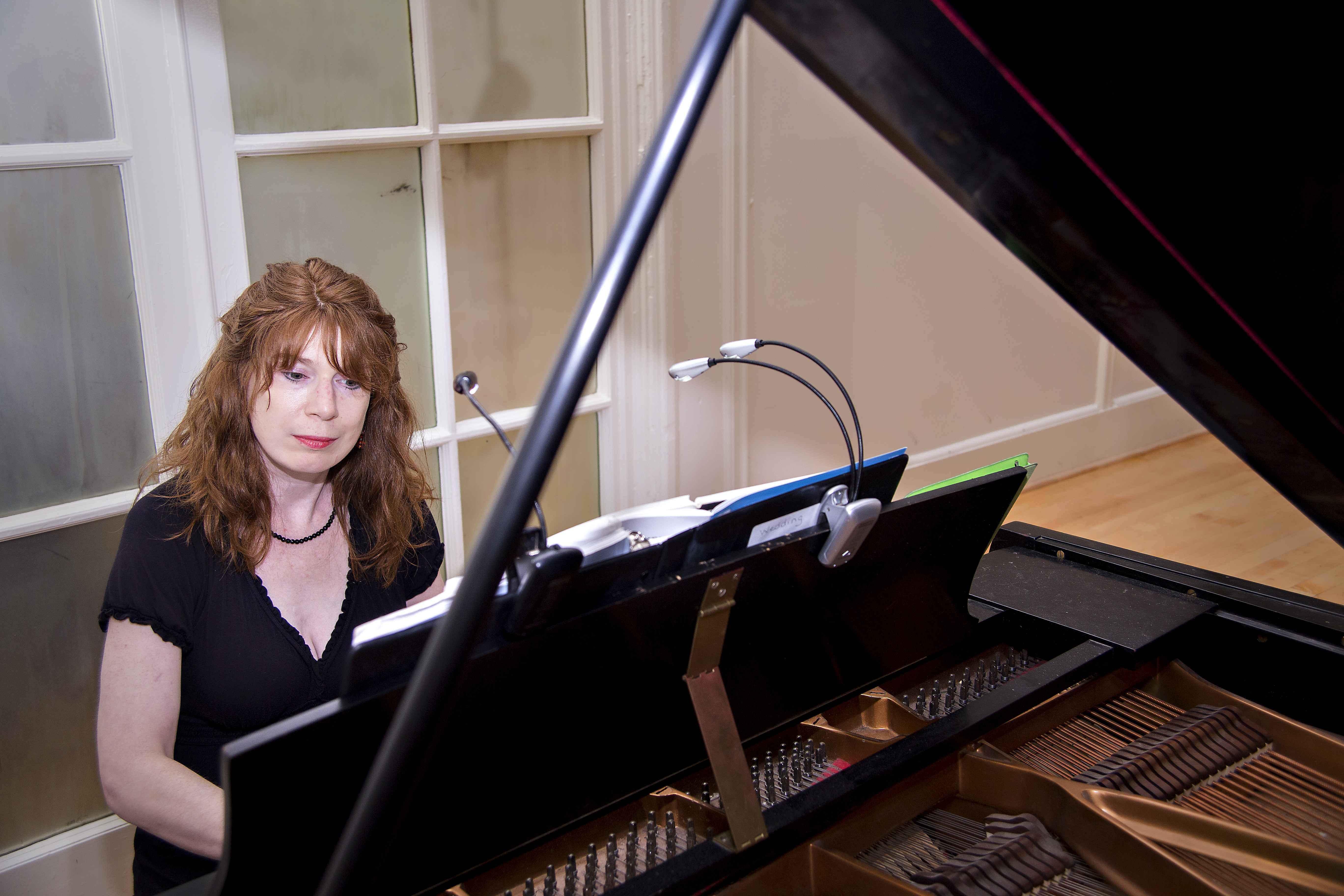 Jenny seated at a grand piano with open sheet music