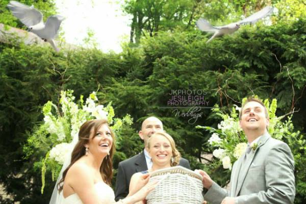 White doves taking flight above a smiling wedding party