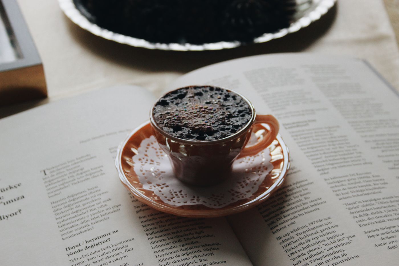 A porcelain coffee cup beside the pages of an open book