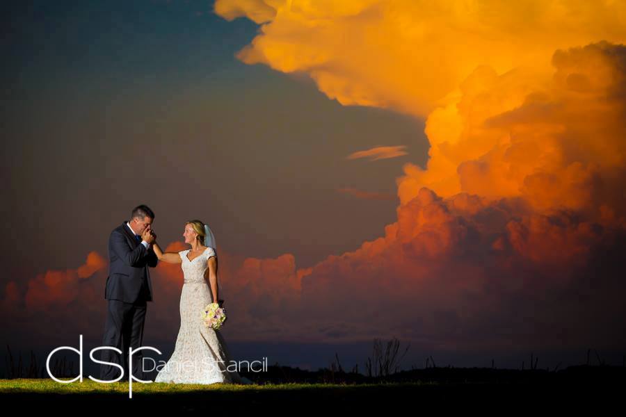 A newlywed couple beneath a dramatic golden sunset