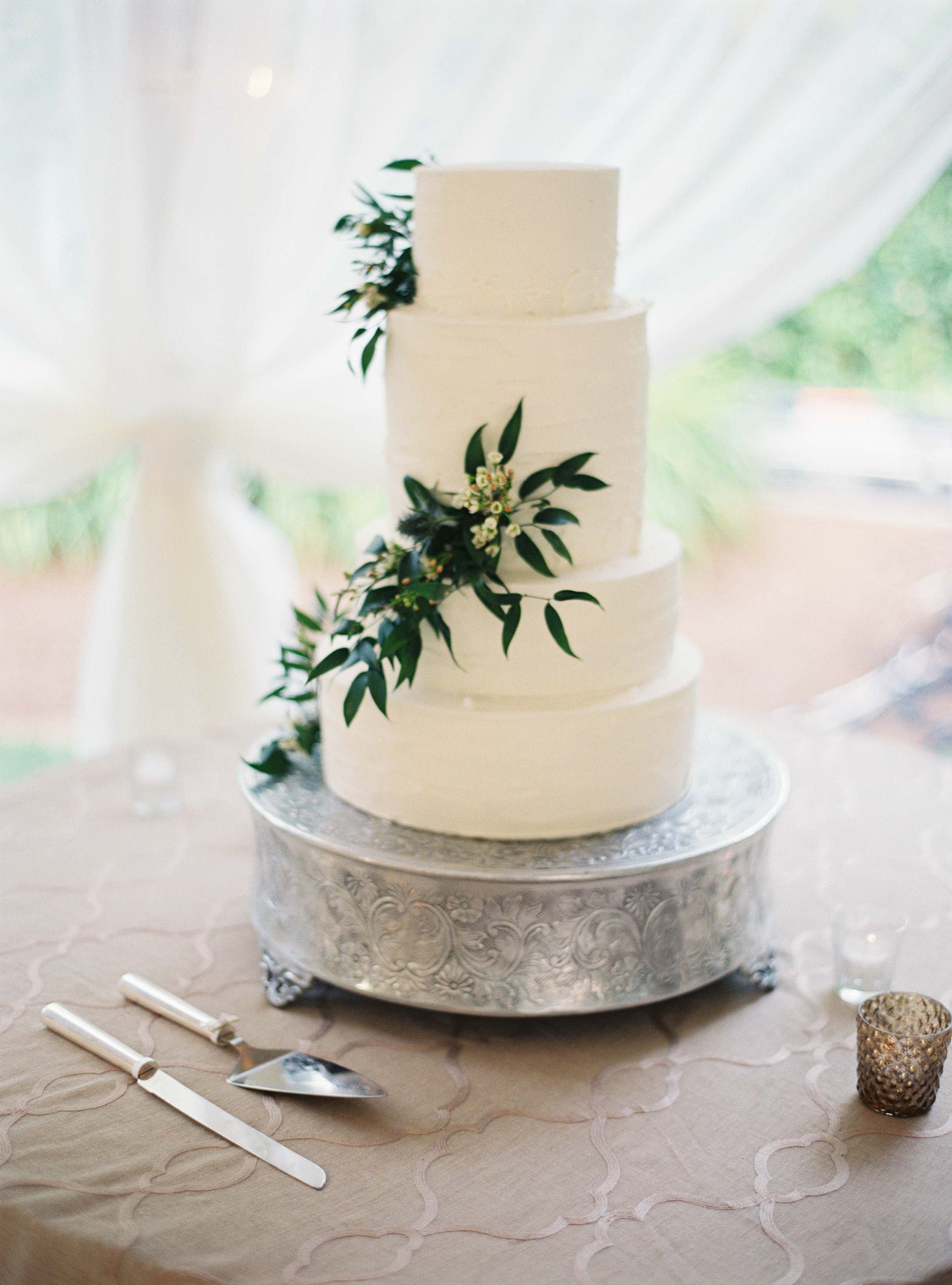 A white wedding cake decorated with delicate greenery