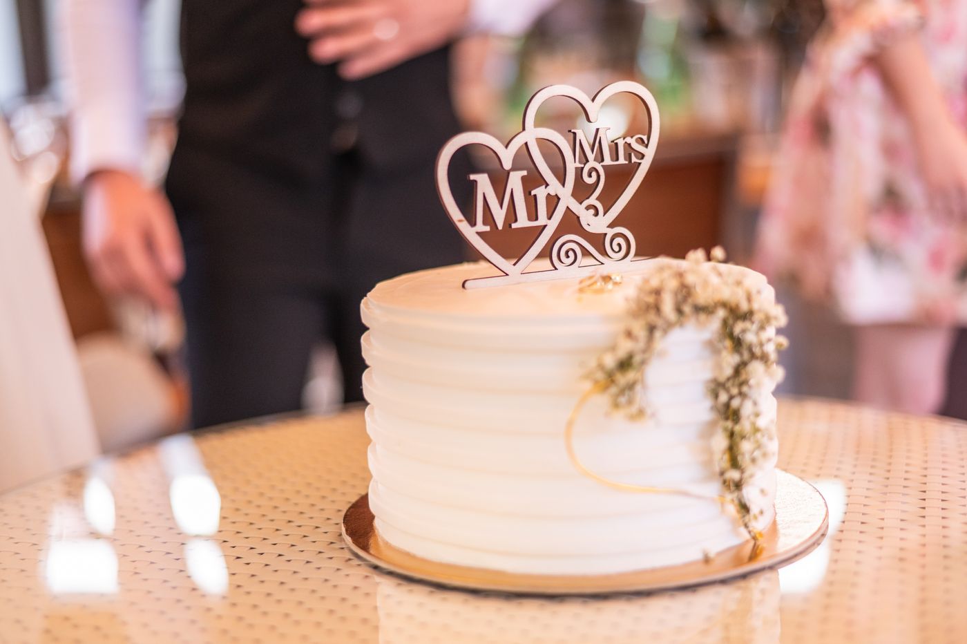 A white wedding cake with floral decorations and a topper