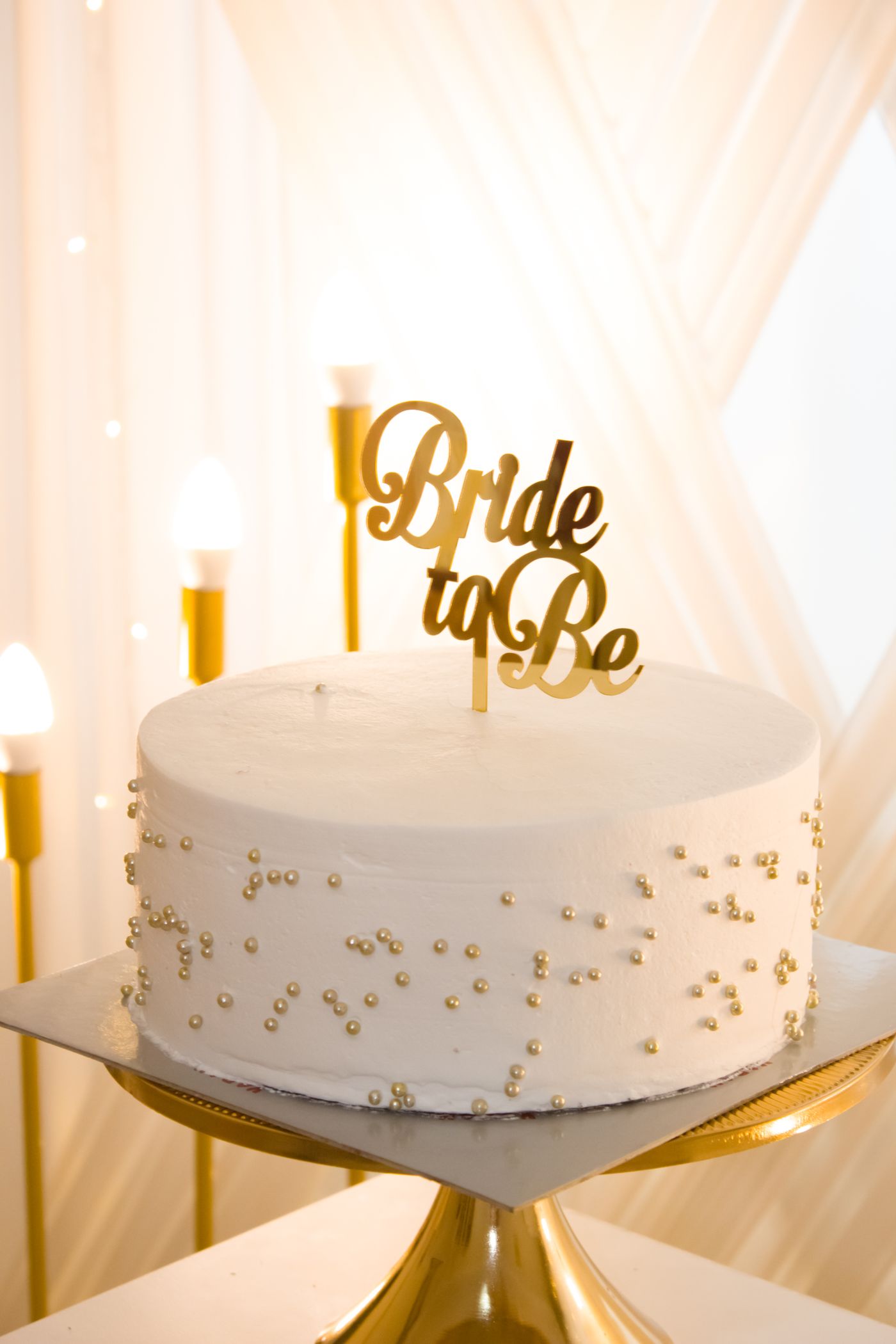 A white bridal shower cake with a Bride to Be topper