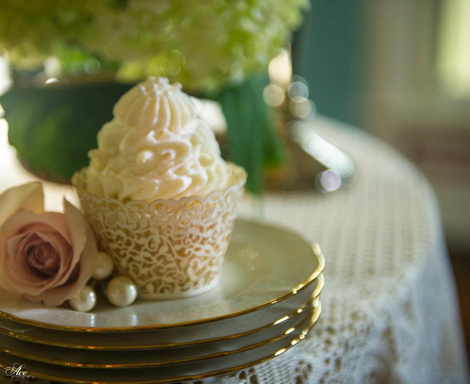 A decorated wedding cupcake with soft flowers in the background