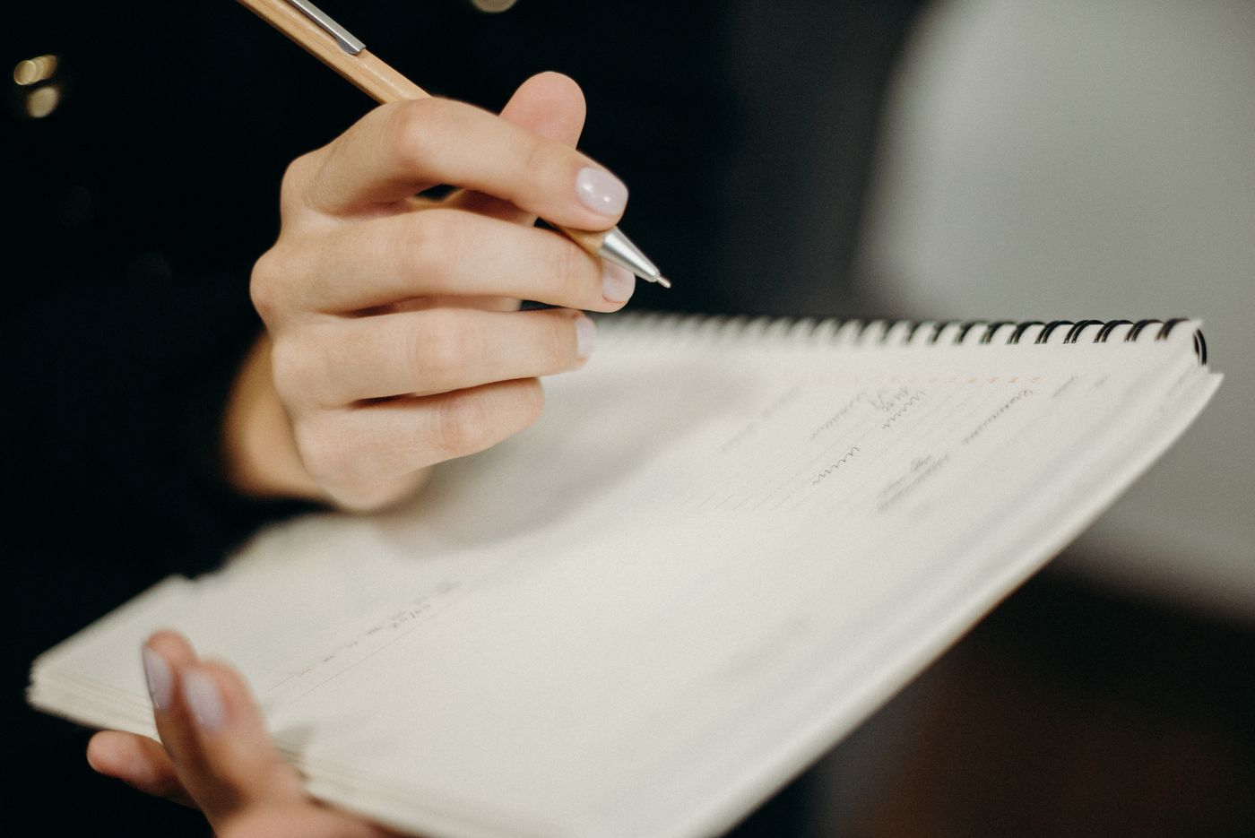 A hand writing in a spiral notebook