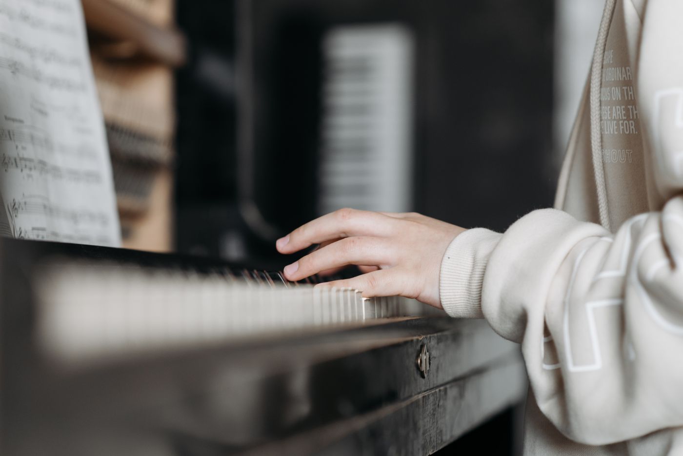Hands playing a piano beneath open sheet music