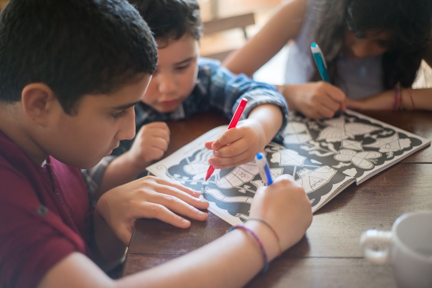 Children coloring together around an activity book
