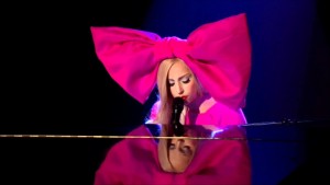 Lady gaga playing the piano in outfit huge pink bow in hair